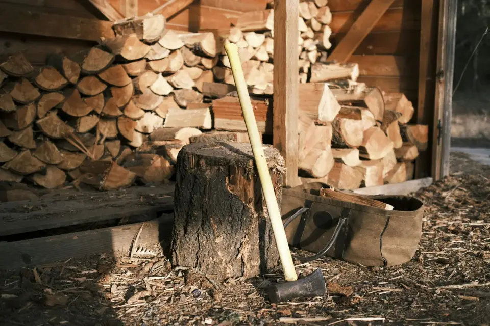 Axe on a chopping block in front of a woodshed stacked with split firewood, Duncan BC