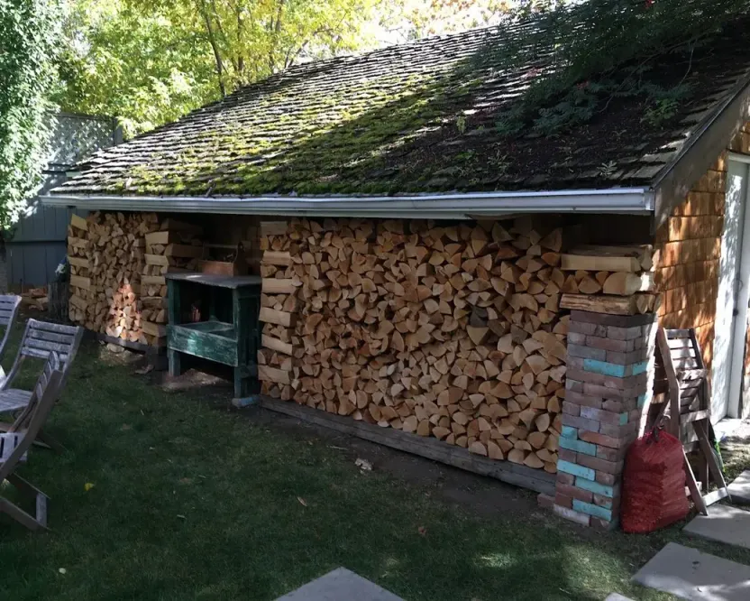 Firewood in Saanich BC: split firewood stacked along a moss-roofed shed
