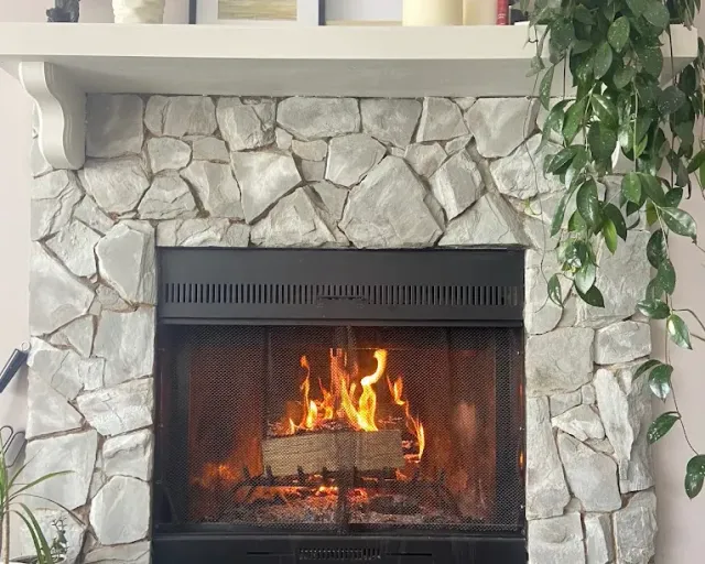 Firewood in Sooke BC: a fire burning in a pale stone fireplace with a white mantel