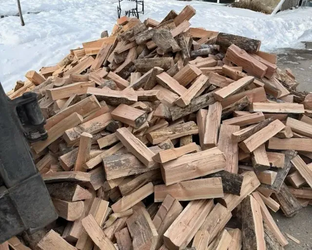 Firewood in Victoria BC: a heap of split firewood beside a snowy yard